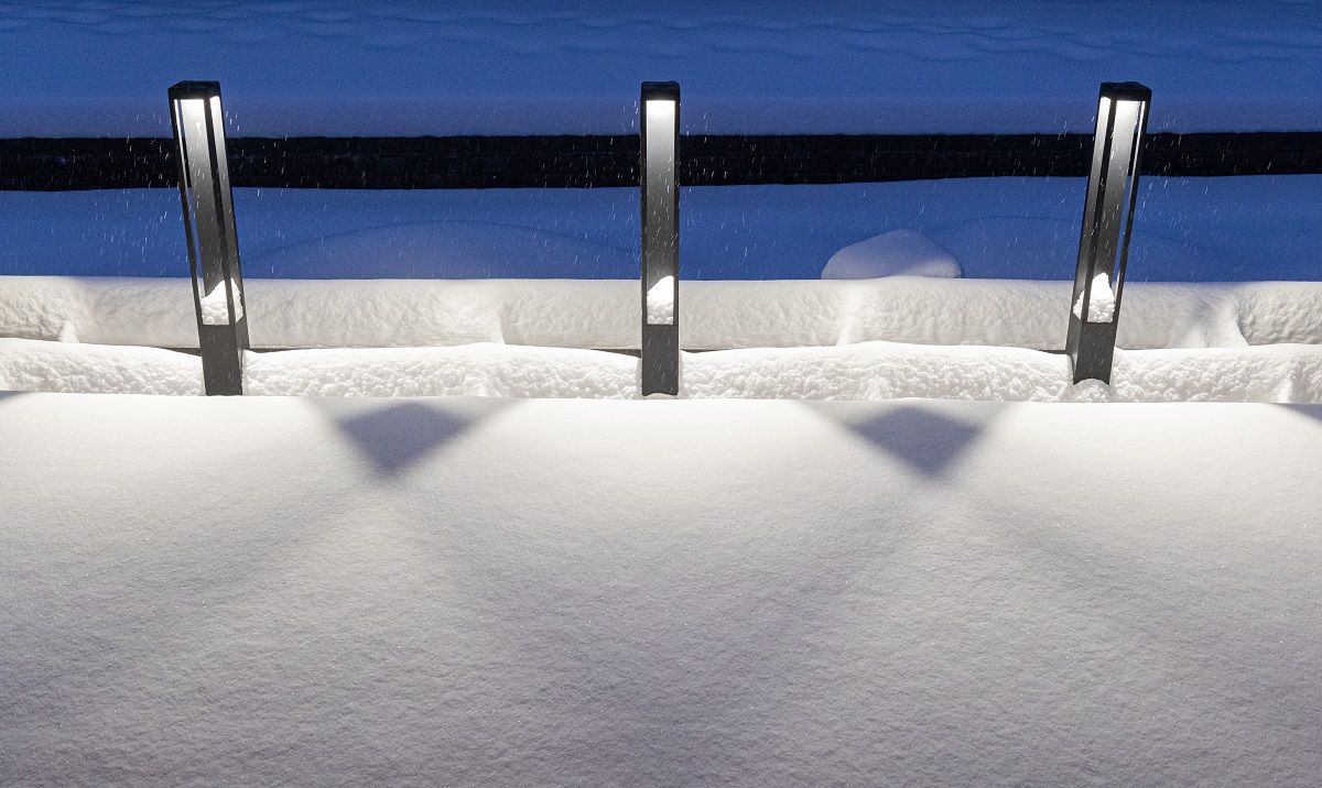 A group of three black Funk Pillar luminaires on the edge of the terrace, in front of the planting pool. The light opens downwards.